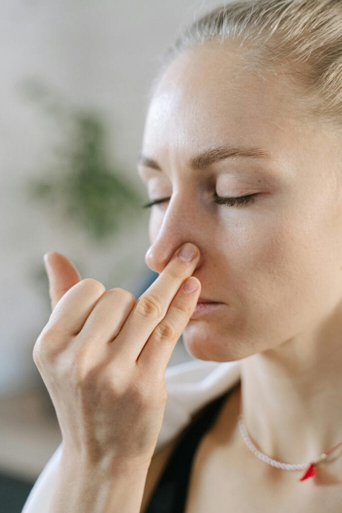 pexels-photo-6648561-6648561 Close-up of a woman doing a breathing exercise with eyes closed indoors.